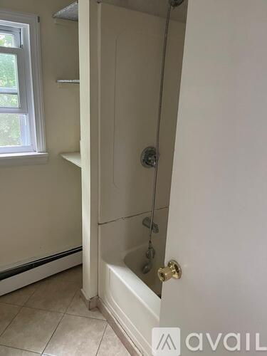 A white bathroom with a tub and a window.