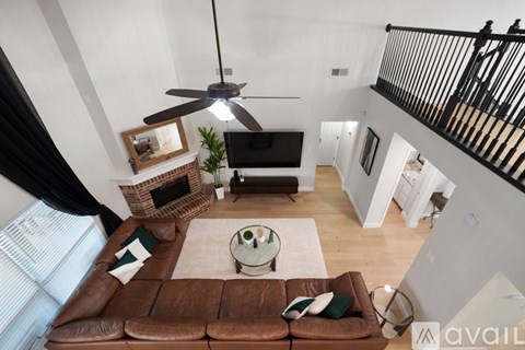 A living room with a brown leather couch and a ceiling fan.