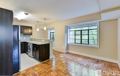 A kitchen with a black refrigerator and wooden flooring.