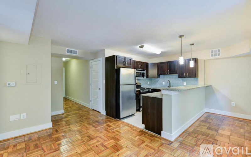 A kitchen with wooden floors and a black refrigerator.