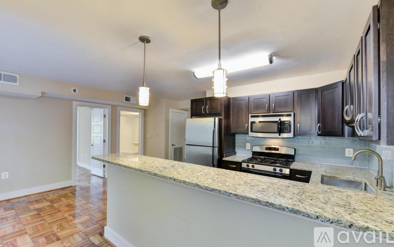 A kitchen with a granite countertop and dark wood cabinets.