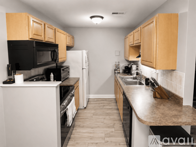 A kitchen with black and white appliances and wooden cabinets.