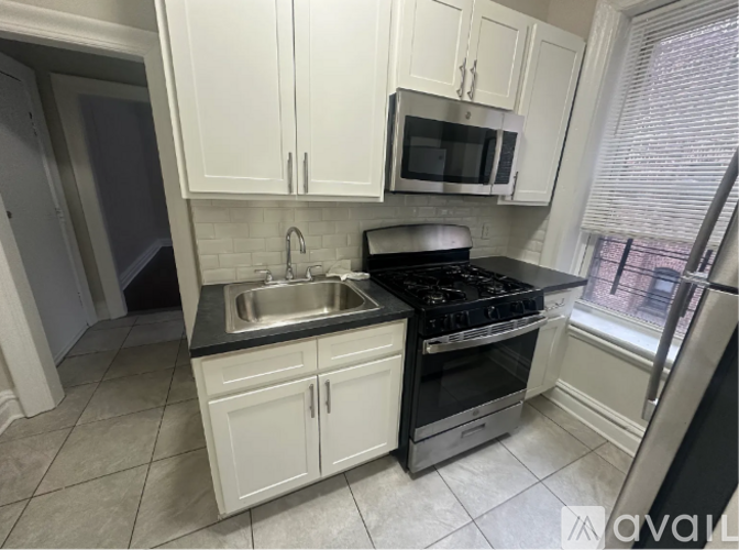 A kitchen with white cabinets and black appliances.