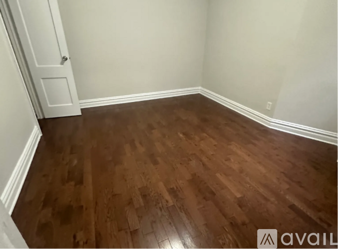 A room with wooden flooring and a white door.