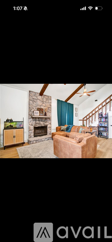 A living room with a stone fireplace and a brown leather couch.