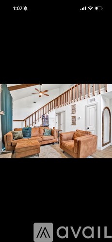 A living room with a brown couch and a ceiling fan.