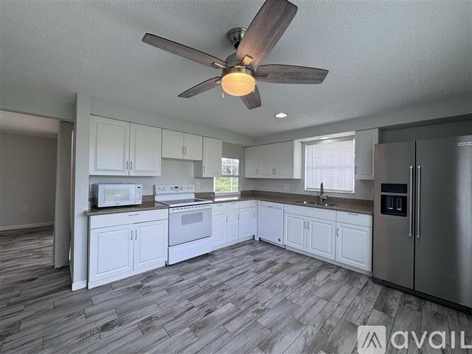 A kitchen with white cabinets and a wooden ceiling fan.
