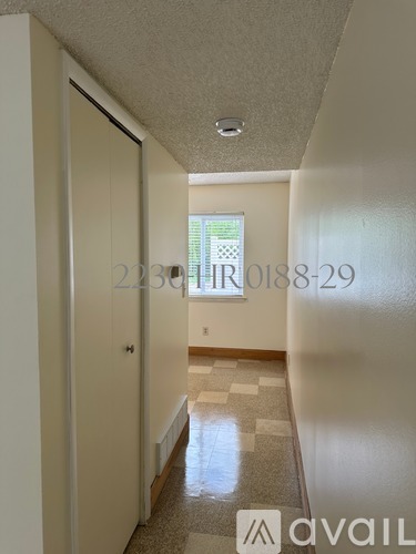 A hallway with a tiled floor and a door on the left.