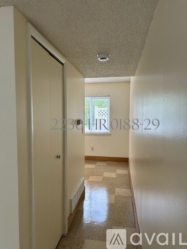A hallway with a tiled floor and a door on the left.