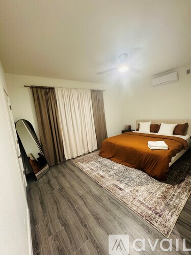 A bedroom with a bed, a mirror, and a rug.