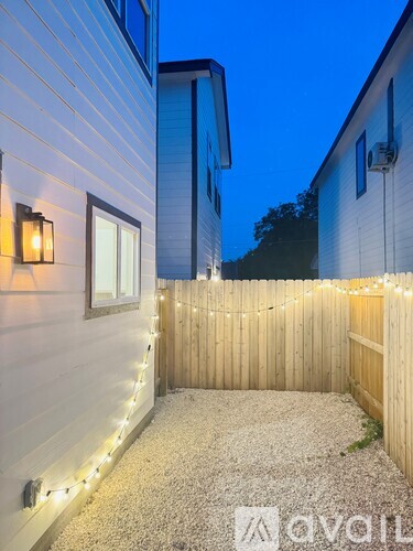 A backyard with a wooden fence and string lights.