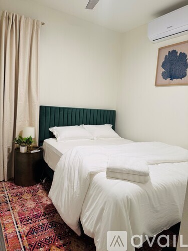 A bedroom with a white bed and a green headboard.