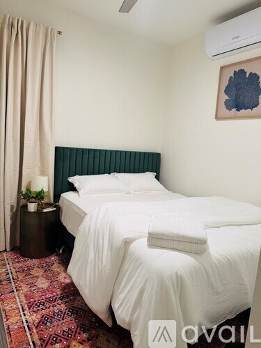 A bedroom with a white bed and a green headboard.