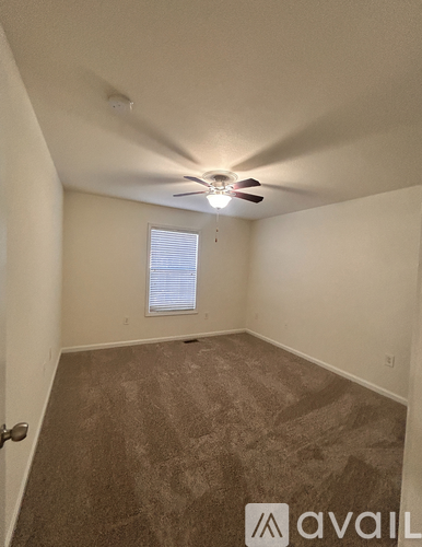 A room with a ceiling fan and a window with blinds.