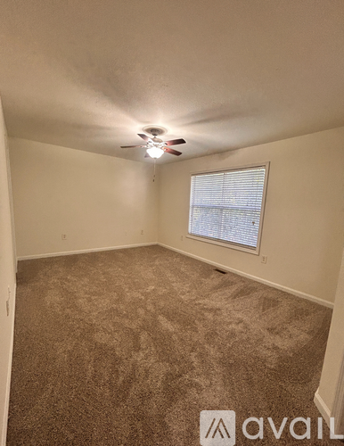 A room with a carpeted floor and a window with blinds.
