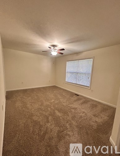 A room with a carpeted floor and a window with blinds.