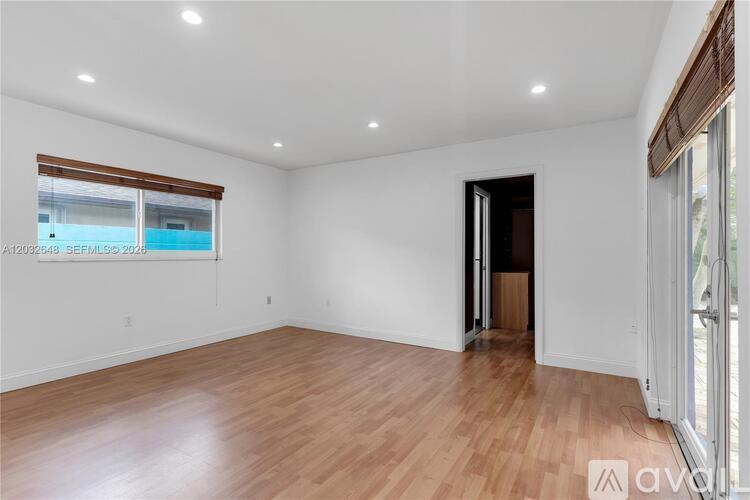 A spacious room with wooden flooring and white walls.