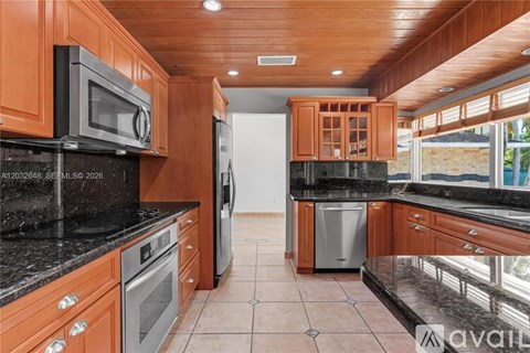 A kitchen with wooden cabinets and black countertops.