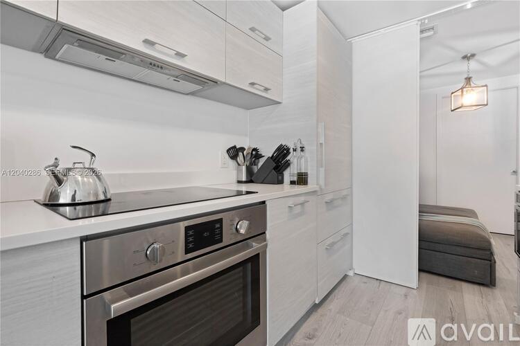 A modern kitchen with a stainless steel oven and white cabinets.