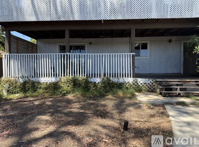 A white house with a porch and a fence.