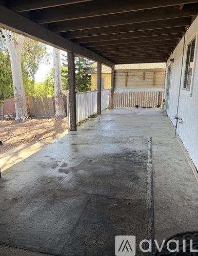 A patio with a white fence and trees in the background.