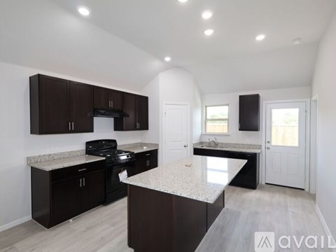 A kitchen with dark brown cabinets and a granite countertop.