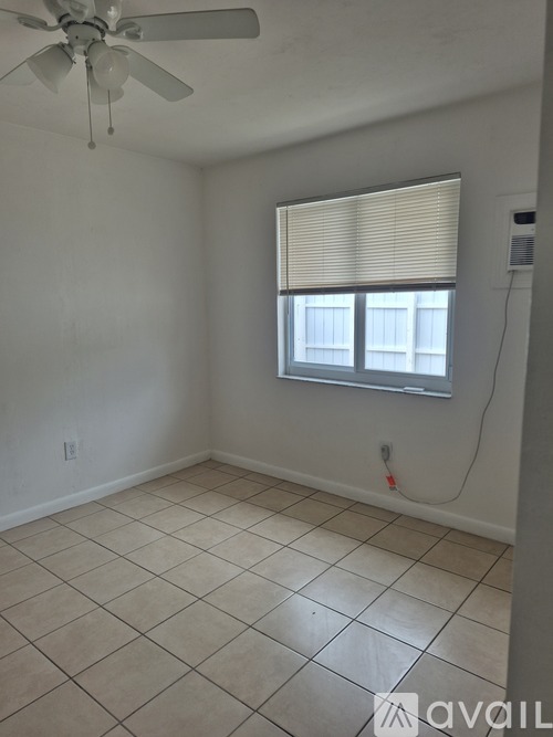 A room with a ceiling fan and a window with blinds.