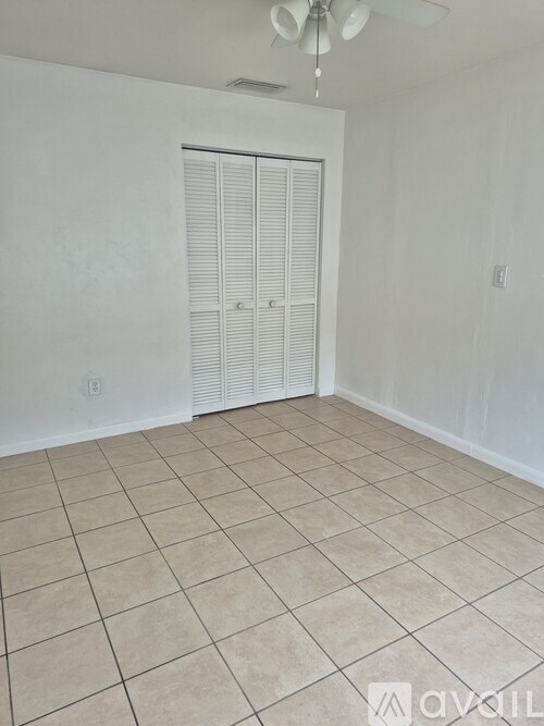 A room with a white door and a ceiling fan.