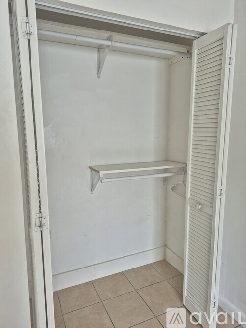A white closet with a shelf and a white door.