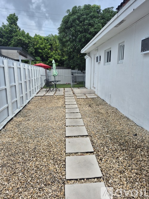 A white building with a gravel pathway leading to it.