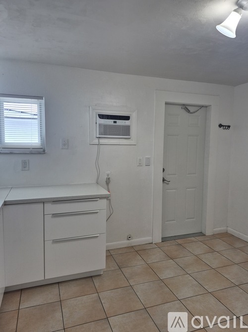 A kitchen with white cabinets and a window.
