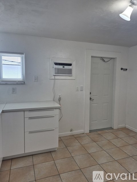 A kitchen with white cabinets and a window.