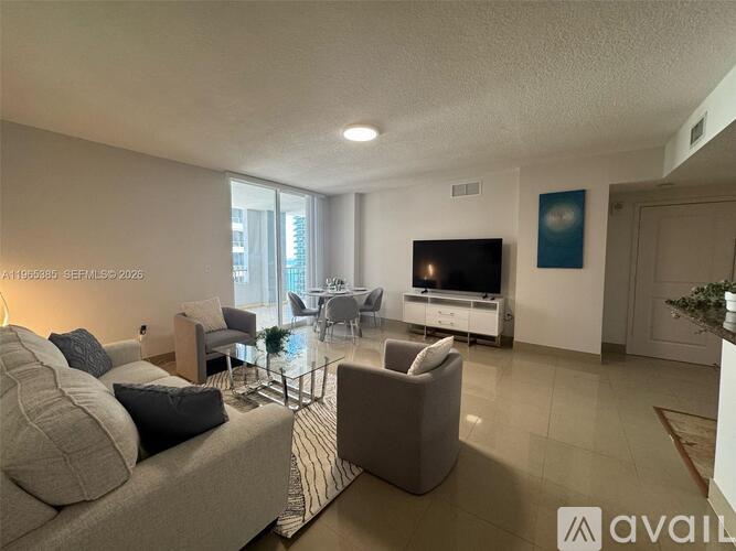 A living room with a grey sofa, a glass coffee table, and a television.