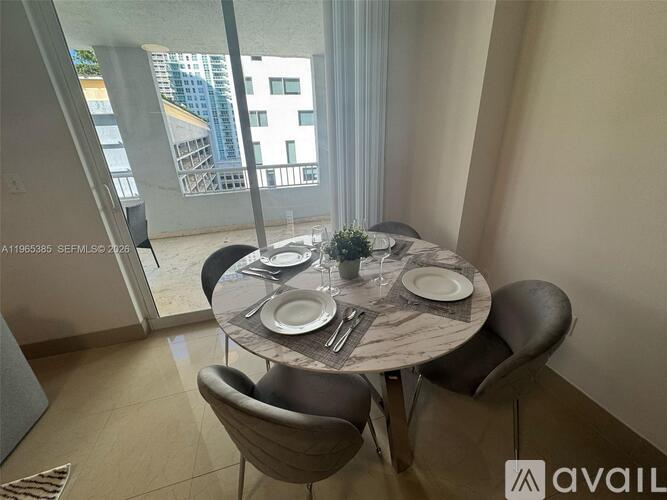 A dining table with chairs and a plant on it in a room with a view of a building outside.