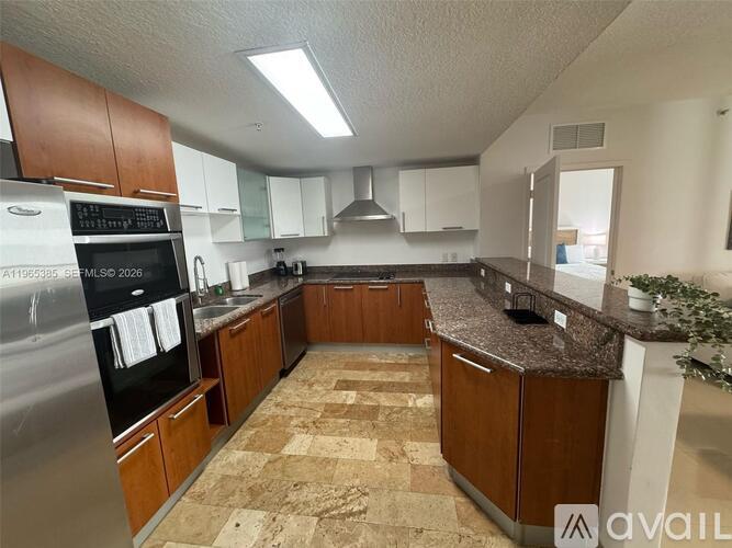 A kitchen with a granite countertop and stainless steel appliances.