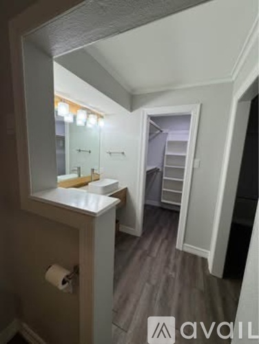A bathroom with a mirror, sink, and toilet paper roll.