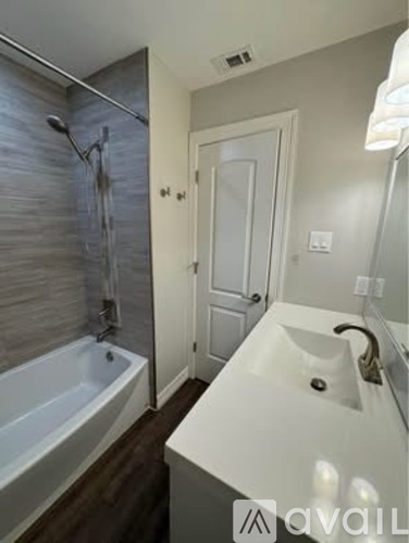 A bathroom with a white sink and a bathtub with a shower head.