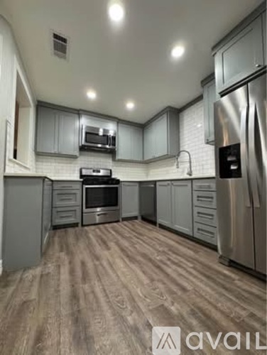 A kitchen with wooden flooring and stainless steel appliances.