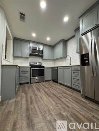 A kitchen with wooden flooring and stainless steel appliances.