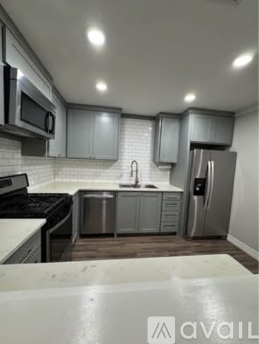 A kitchen with a white counter top and stainless steel appliances.