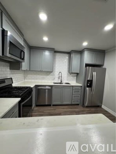 A kitchen with a white counter top and stainless steel appliances.