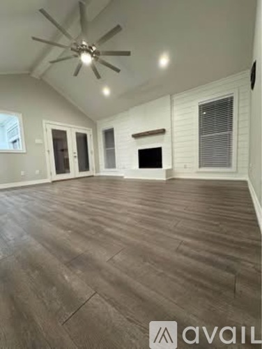 A spacious room with a ceiling fan and wooden flooring.