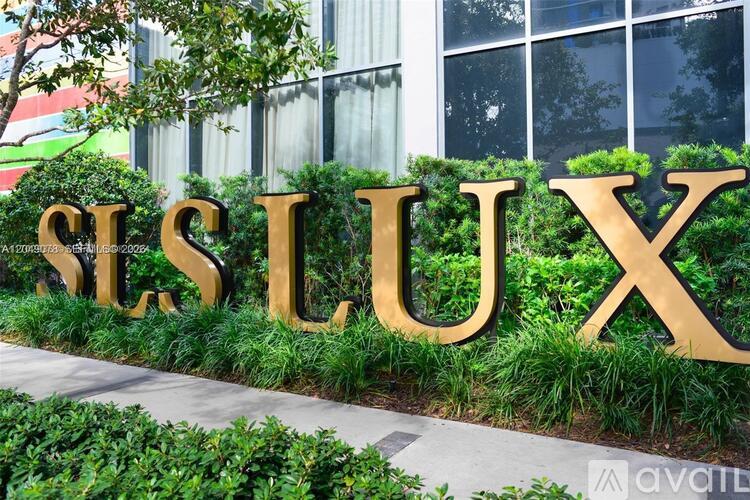 A large gold sign spelling out "SLUSK" is surrounded by greenery.