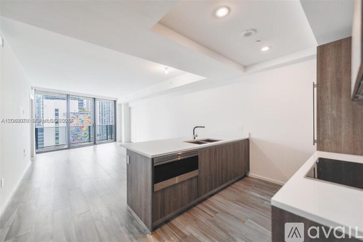 A modern kitchen with wooden cabinets and a large window.