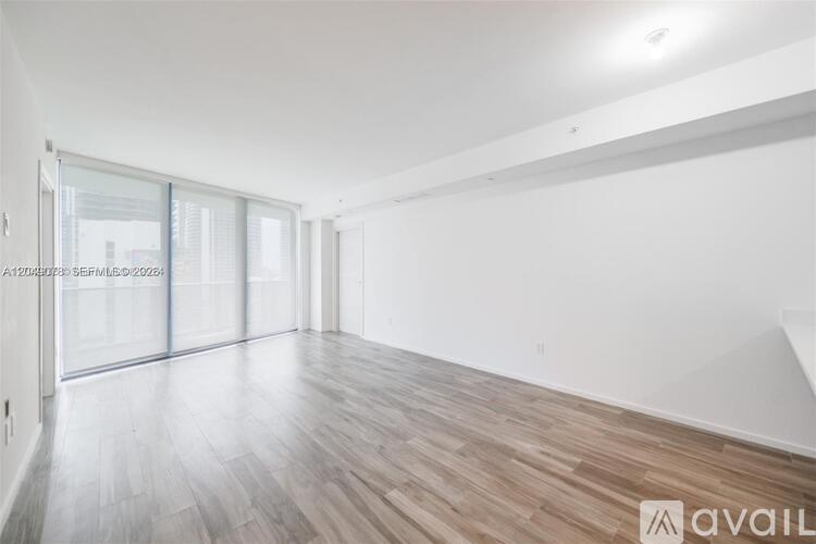 A spacious room with wooden flooring and white walls.
