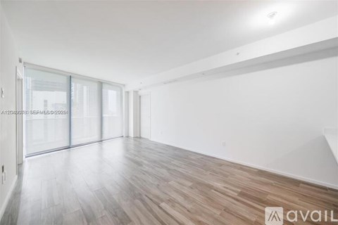 A spacious room with wooden flooring and white walls.
