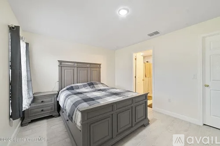 A bedroom with a large bed and a window with curtains.