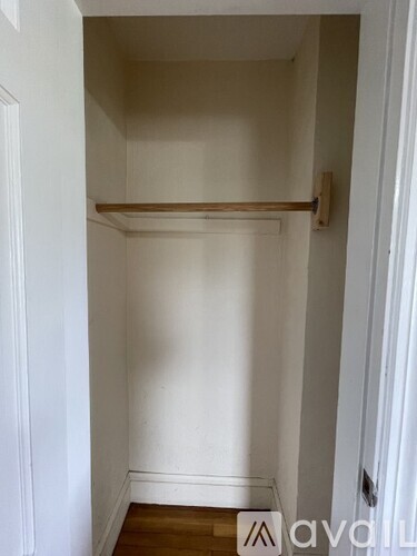 A small white closet with a wooden rod on the wall.