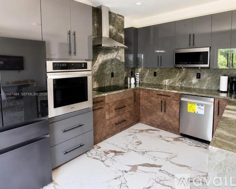 A kitchen with a stainless steel refrigerator and a marble countertop.