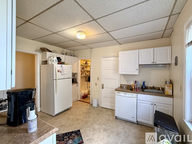 A kitchen with white cabinets and a white refrigerator.